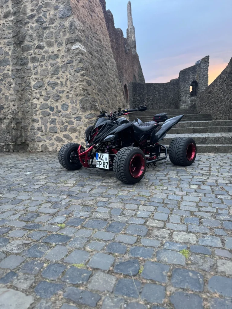 Quad an einer Burgmauer mit pulverbeschichteten Felgen und Rahmenteilen